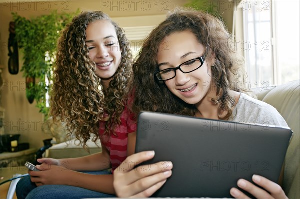 Mixed race teenage girls relaxing on sofa