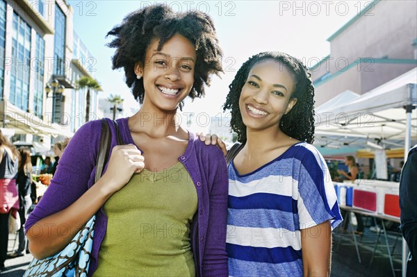 Women smiling together at outdoor market