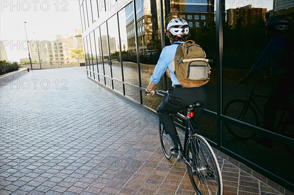 Caucasian businessman riding bicycle outside building
