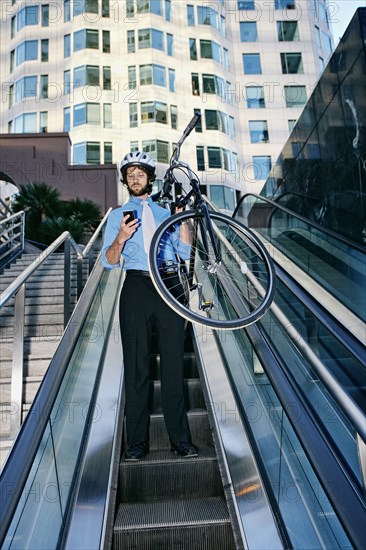 Caucasian businessman carrying bicycle on escalator