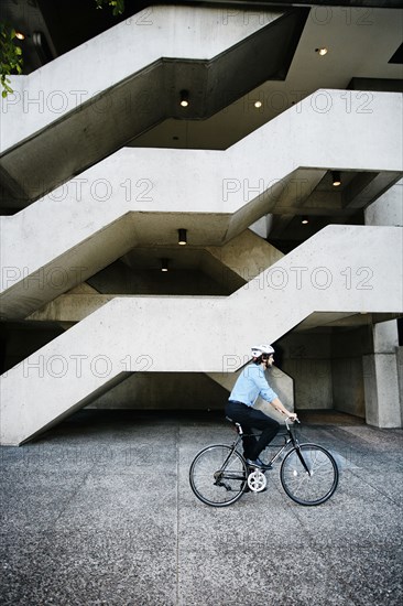 Caucasian businessman riding bicycle outside office building