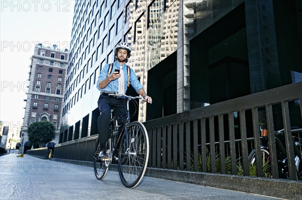 Caucasian businessman using cell phone on bicycle