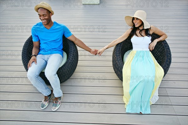 Couple holding hands in wicker chairs