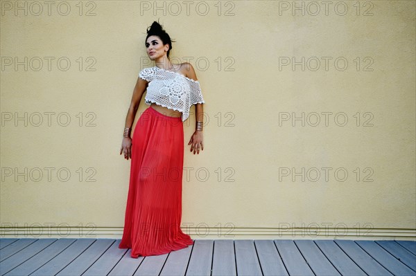 Middle Eastern woman leaning against wall outdoors