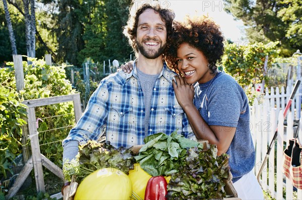 Couple harvesting vegetables in garden