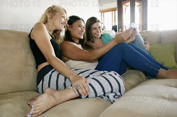 Women taking self-portrait together on sofa