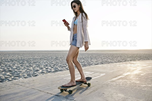 Caucasian woman skating on beach