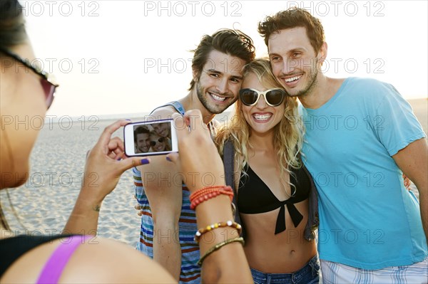 Friends taking pictures together on beach