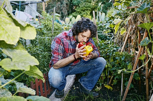 Caucasian man smelling peppers in garden