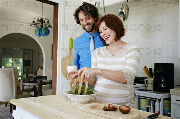 Pregnant Caucasian couple cooking in kitchen