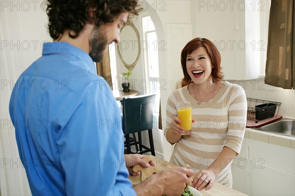 Pregnant Caucasian couple cooking in kitchen