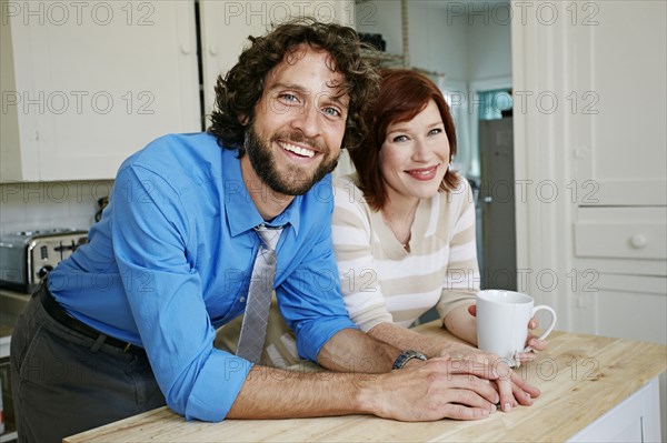 Pregnant Caucasian couple smiling in kitchen