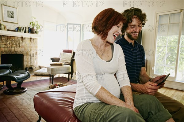 Pregnant Caucasian couple using digital tablet