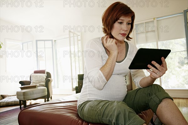 Pregnant Caucasian woman using digital tablet