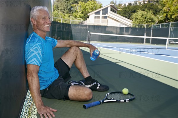Caucasian man sitting on tennis court