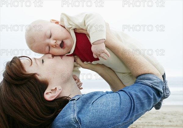 Mother kissing baby on beach