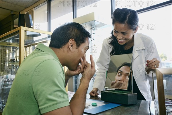 Optometrist helping patient with contacts in office