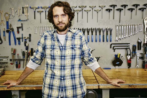 Caucasian man smiling in bicycle repair shop