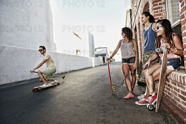 Friends riding longboards on city street