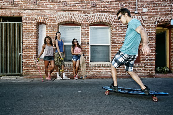 Friends riding longboards on city street