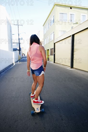 Woman riding longboard on city street