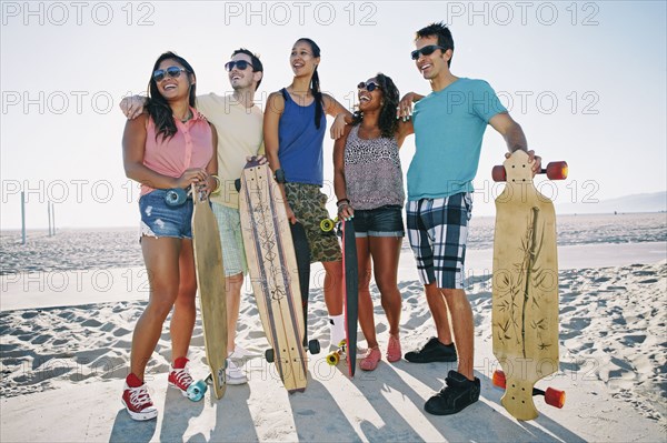 Friends holding longboards on beach