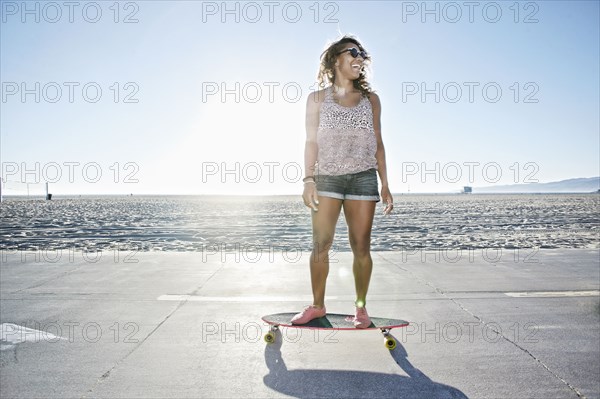 African American woman riding longboard on beach