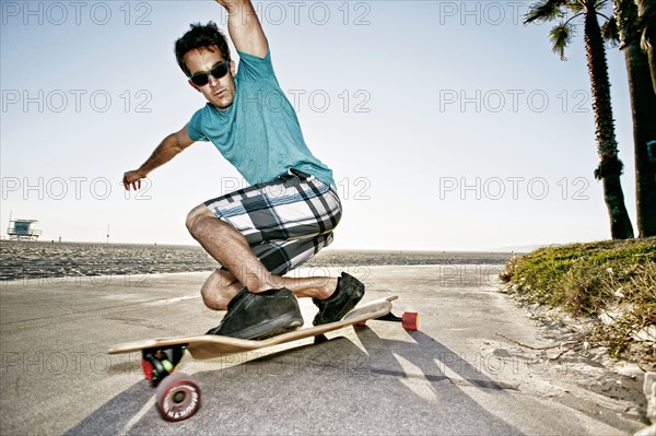 Caucasian man riding longboard on beach