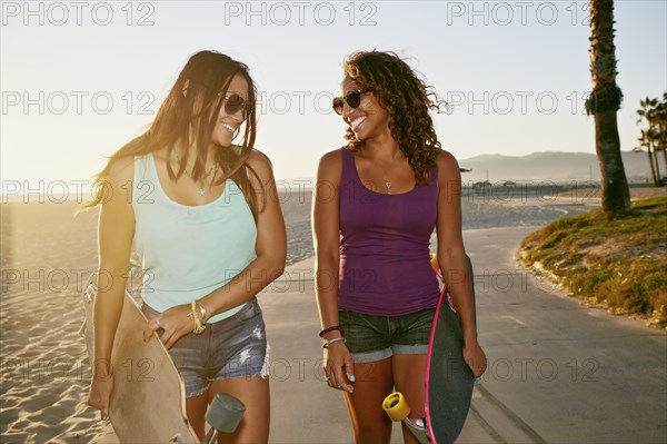 Women carrying longboards on beach