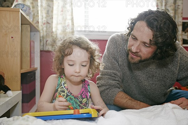 Caucasian father and daughter playing in bedroom