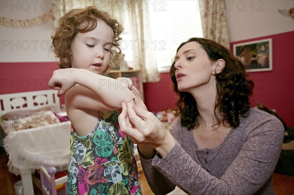 Caucasian mother examining daughter's scrape