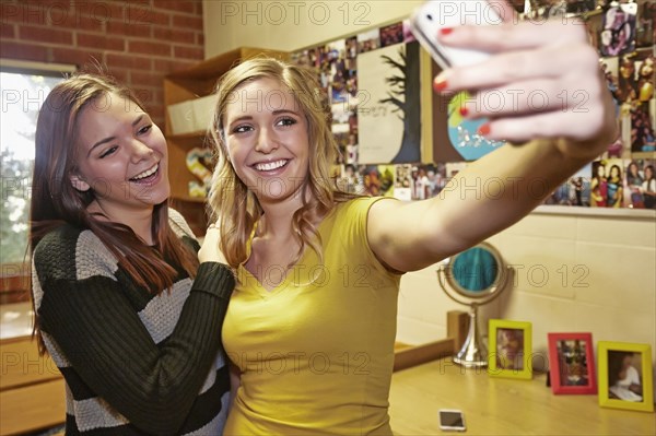 Caucasian students taking pictures in dorm room