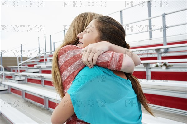 Teenage girls hugging on bleachers