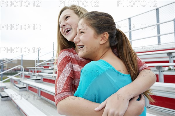 Teenage girls hugging on bleachers