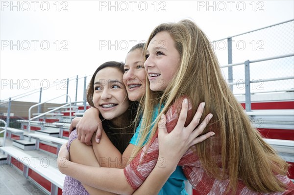 Teenage girls hugging on bleachers