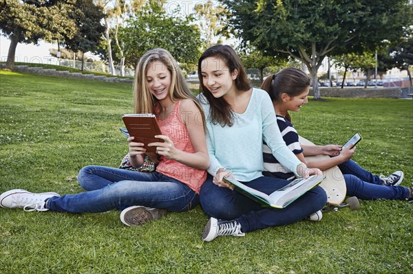 Teenage girls reading in grass