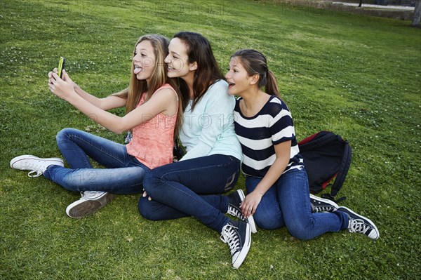 Teenage girls taking pictures in grass