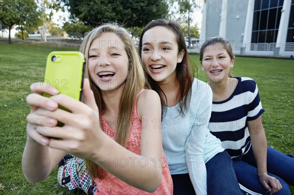 Teenage girls taking pictures in grass