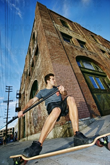 Caucasian man riding skateboard with land paddle