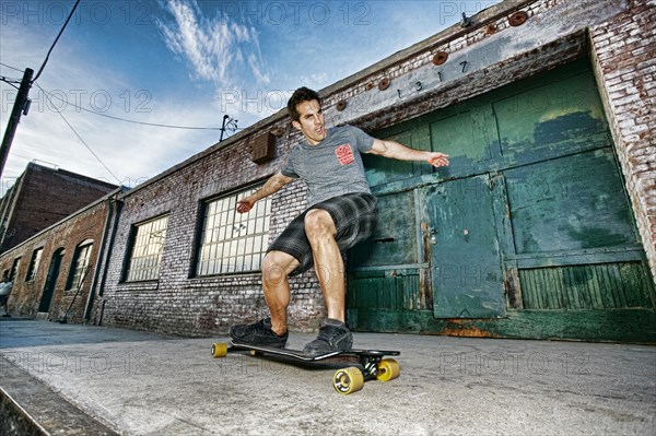 Caucasian man riding skateboard on city street