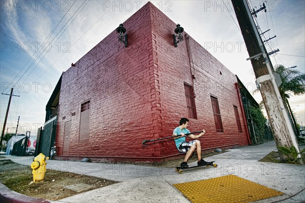 Caucasian man riding skateboard with land paddle