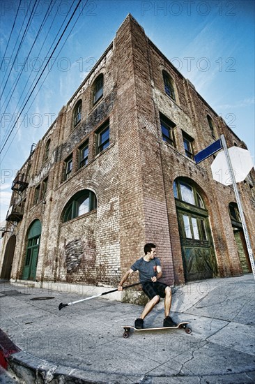 Caucasian man riding skateboard with land paddle