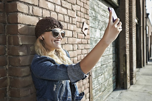 Woman taking picture of herself on city street