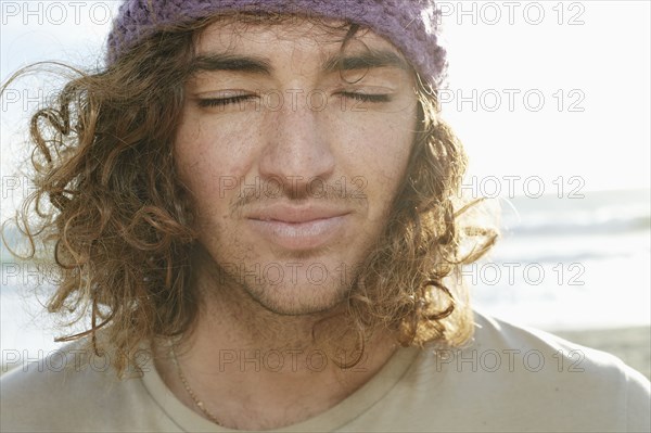 Caucasian man with eyes closed on beach