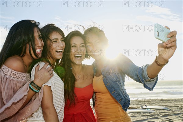 Women taking pictures together on beach