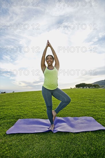 Pregnant woman practicing yoga in park
