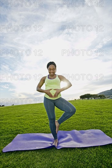 Pregnant woman practicing yoga in park