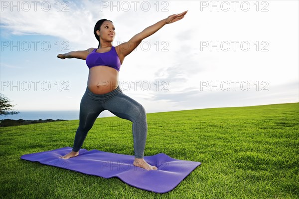 Pregnant woman practicing yoga in park