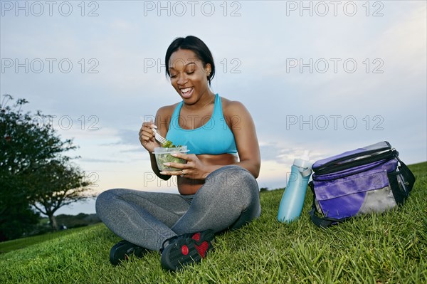 Pregnant woman eating salad in park