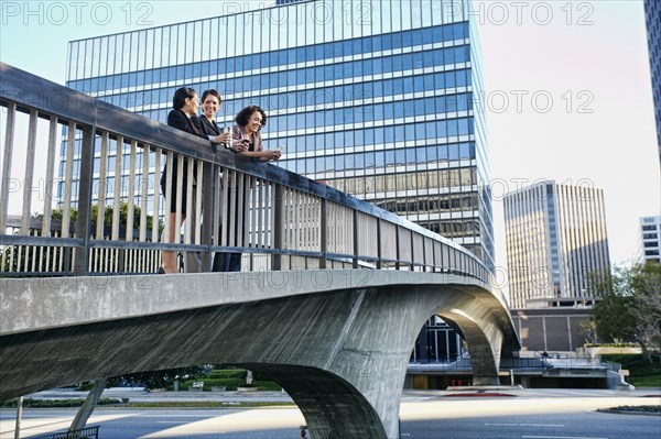 Businesswomen talking on urban sky bridge